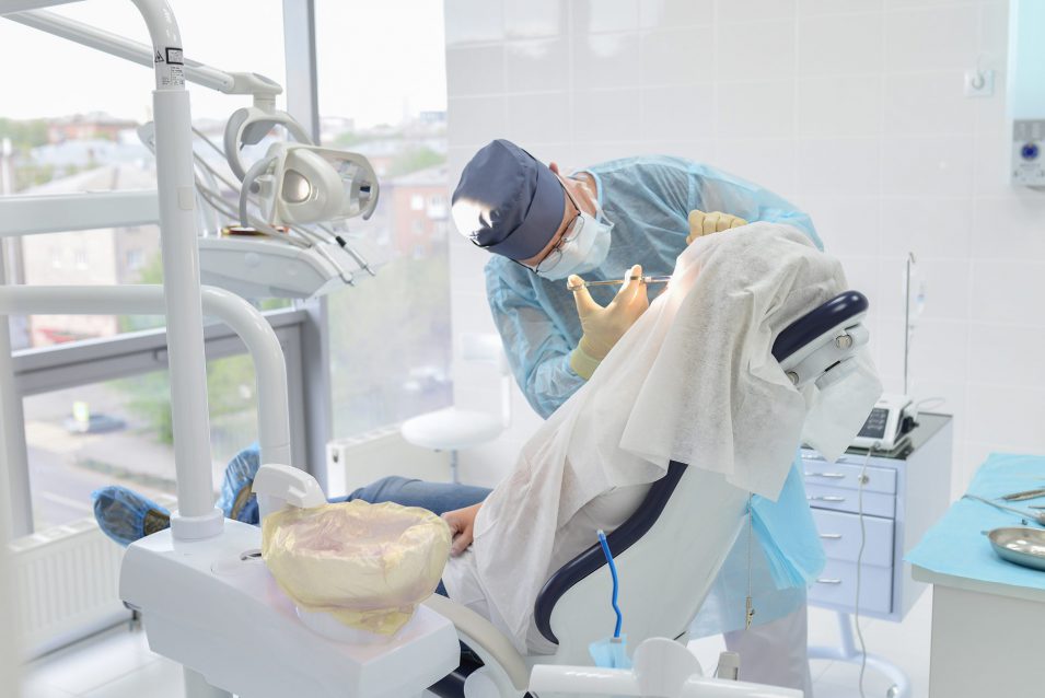 Emergency dentist performs dental surgery operation in modern dentist clinic